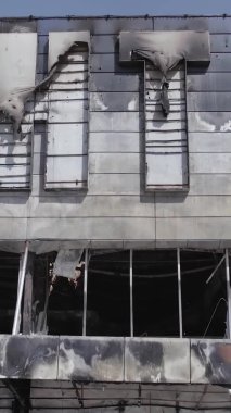Bu dikey video, Bucha, Ukrayna 'da bir alışveriş merkezinin savaş tarafından tahrip edildiğini gösteriyor. Ağır çekim, gri, renksiz, düz.