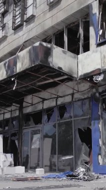 Bu dikey video, Bucha, Ukrayna 'da bir alışveriş merkezinin savaş tarafından tahrip edildiğini gösteriyor. Ağır çekim, gri, renksiz, düz.