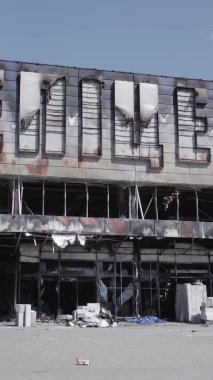 Bu dikey video, Bucha, Ukrayna 'da bir alışveriş merkezinin savaş tarafından tahrip edildiğini gösteriyor. Ağır çekim, gri, renksiz, düz.