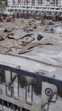 Bu dikey video, Bucha, Ukrayna 'da bir alışveriş merkezinin savaş tarafından tahrip edildiğini gösteriyor. Ağır çekim, gri, renksiz, düz.