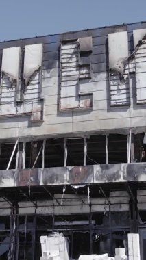 Bu dikey video, Bucha, Ukrayna 'da bir alışveriş merkezinin savaş tarafından tahrip edildiğini gösteriyor. Ağır çekim, gri, renksiz, düz.