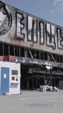 Bu dikey video, Bucha, Ukrayna 'da bir alışveriş merkezinin savaş tarafından tahrip edildiğini gösteriyor. Ağır çekim, gri, renksiz, düz.