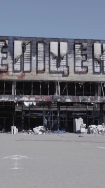 Bu dikey video, Bucha, Ukrayna 'da bir alışveriş merkezinin savaş tarafından tahrip edildiğini gösteriyor. Ağır çekim, gri, renksiz, düz.