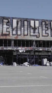 Bu dikey video, Bucha, Ukrayna 'da bir alışveriş merkezinin savaş tarafından tahrip edildiğini gösteriyor. Ağır çekim, gri, renksiz, düz.