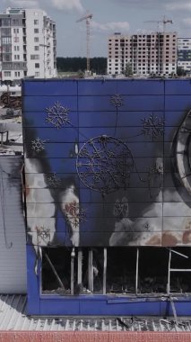 Bu dikey video, Bucha, Ukrayna 'da bir alışveriş merkezinin savaş tarafından tahrip edildiğini gösteriyor. Ağır çekim, gri, renksiz, düz.