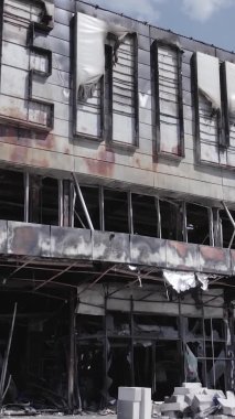 Bu dikey video, Bucha, Ukrayna 'da bir alışveriş merkezinin savaş tarafından tahrip edildiğini gösteriyor. Ağır çekim, gri, renksiz, düz.