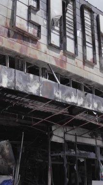 Bu dikey video, Bucha, Ukrayna 'da bir alışveriş merkezinin savaş tarafından tahrip edildiğini gösteriyor. Ağır çekim, gri, renksiz, düz.