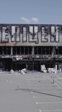 Bu dikey video, Bucha, Ukrayna 'da bir alışveriş merkezinin savaş tarafından tahrip edildiğini gösteriyor. Ağır çekim, gri, renksiz, düz.