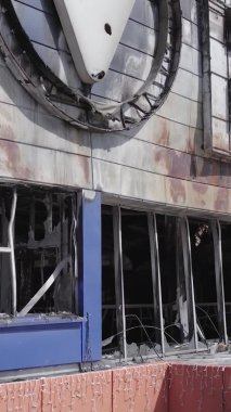 Bu dikey video, Bucha, Ukrayna 'da bir alışveriş merkezinin savaş tarafından tahrip edildiğini gösteriyor. Ağır çekim, gri, renksiz, düz.