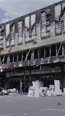 Bu dikey video, Bucha, Ukrayna 'da bir alışveriş merkezinin savaş tarafından tahrip edildiğini gösteriyor. Ağır çekim, gri, renksiz, düz.