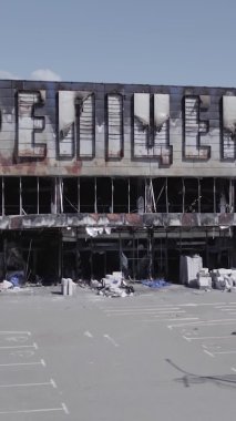 Bu dikey video, Bucha, Ukrayna 'da bir alışveriş merkezinin savaş tarafından tahrip edildiğini gösteriyor. Ağır çekim, gri, renksiz, düz.