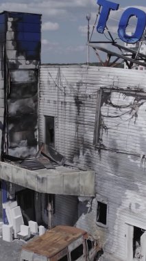 Bu dikey video, Bucha, Ukrayna 'da bir alışveriş merkezinin savaş tarafından tahrip edildiğini gösteriyor. Ağır çekim, gri, renksiz, düz.