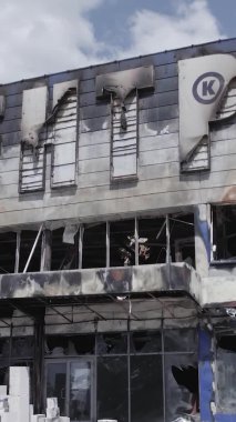 Bu dikey video, Bucha, Ukrayna 'da bir alışveriş merkezinin savaş tarafından tahrip edildiğini gösteriyor. Ağır çekim, gri, renksiz, düz.