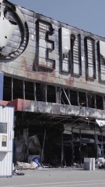 Bu dikey video, Bucha, Ukrayna 'da bir alışveriş merkezinin savaş tarafından tahrip edildiğini gösteriyor. Ağır çekim, gri, renksiz, düz.