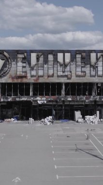 Bu dikey video, Bucha, Ukrayna 'da bir alışveriş merkezinin savaş tarafından tahrip edildiğini gösteriyor. Ağır çekim, gri, renksiz, düz.