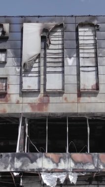 Bu dikey video, Bucha, Ukrayna 'da bir alışveriş merkezinin savaş tarafından tahrip edildiğini gösteriyor. Ağır çekim, gri, renksiz, düz.