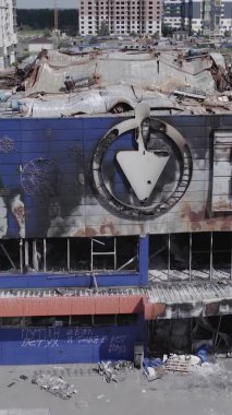 Bu dikey video, Bucha, Ukrayna 'da bir alışveriş merkezinin savaş tarafından tahrip edildiğini gösteriyor. Ağır çekim, gri, renksiz, düz.
