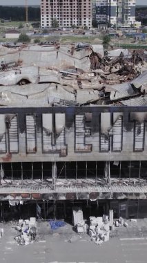 Bu dikey video, Bucha, Ukrayna 'da bir alışveriş merkezinin savaş tarafından tahrip edildiğini gösteriyor. Ağır çekim, gri, renksiz, düz.