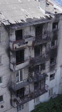 This stock vertical video shows a destroyed building in the city of Makariv during the war in Ukraine, grey, no color, flat