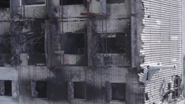 This stock vertical video shows a destroyed building in the city of Makariv during the war in Ukraine, grey, no color, flat