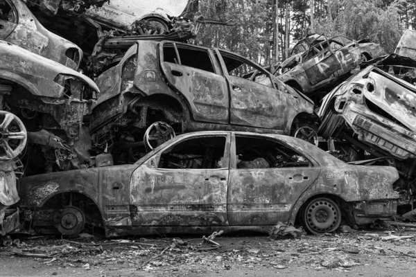 Bu siyah-beyaz fotoğraf Irpin, Bucha bölgesinde bir kurşun ve yanmış araba damlasını gösteriyor.