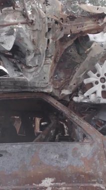 Bu stok dikey video Irpin, Bucha bölgesinde gri, düz, renksiz, yanmış arabaları gösteriyor.