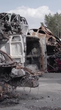 Bu stok dikey video Irpin, Bucha bölgesinde gri, düz, renksiz, yanmış arabaları gösteriyor.