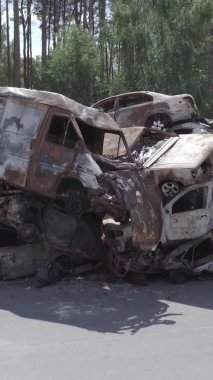 Bu stok dikey video Irpin, Bucha bölgesinde gri, düz, renksiz, yanmış arabaları gösteriyor.