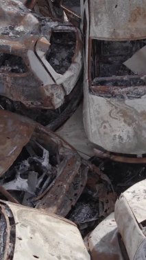 Bu stok dikey video Irpin, Bucha bölgesinde gri, düz, renksiz, yanmış arabaları gösteriyor.