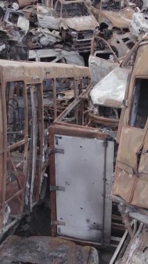 Bu stok dikey video Irpin, Bucha bölgesinde gri, düz, renksiz, yanmış arabaları gösteriyor.