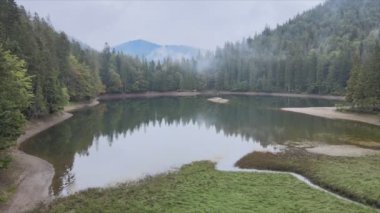 This stock video shows an aerial view of Synevyr Lake in the Carpathian Mountains, Ukraine in 8K resolution