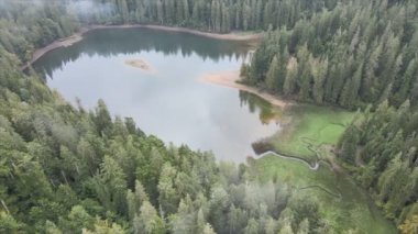 This stock video shows an aerial view of Synevyr Lake in the Carpathian Mountains, Ukraine in 8K resolution