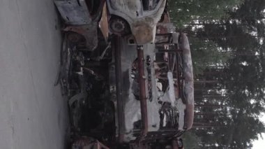 This stock vertical video shows a dump of shot and burned cars in Irpin, Bucha district , grey, flat video