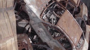 This stock vertical video shows a dump of shot and burned cars in Irpin, Bucha district , grey, flat video