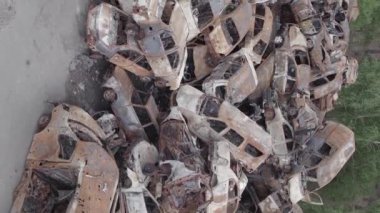 This stock vertical video shows a dump of shot and burned cars in Irpin, Bucha district , grey, flat video
