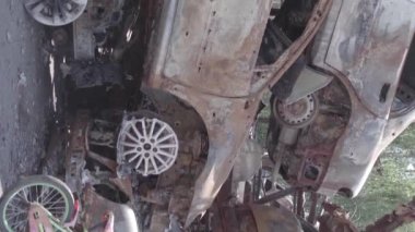 This stock vertical video shows a dump of shot and burned cars in Irpin, Bucha district , grey, flat video