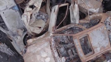 This stock vertical video shows a dump of shot and burned cars in Irpin, Bucha district , grey, flat video