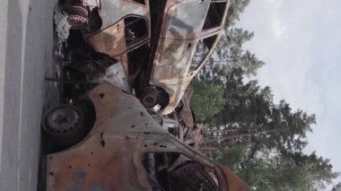 This stock vertical video shows a dump of shot and burned cars in Irpin, Bucha district , grey, flat video