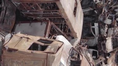 This stock vertical video shows a dump of shot and burned cars in Irpin, Bucha district , grey, flat video