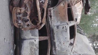 This stock vertical video shows a dump of shot and burned cars in Irpin, Bucha district , grey, flat video