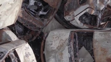 This stock vertical video shows a dump of shot and burned cars in Irpin, Bucha district , grey, flat video