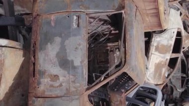 This stock vertical video shows a dump of shot and burned cars in Irpin, Bucha district , grey, flat video