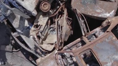 This stock vertical video shows a dump of shot and burned cars in Irpin, Bucha district , grey, flat video