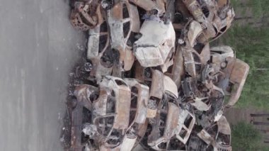 This stock vertical video shows a dump of shot and burned cars in Irpin, Bucha district , grey, flat video