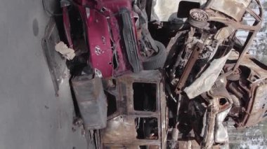 This stock vertical video shows a dump of shot and burned cars in Irpin, Bucha district , grey, flat video