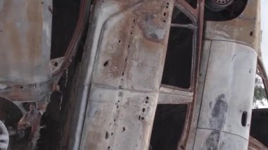 This stock vertical video shows a dump of shot and burned cars in Irpin, Bucha district , grey, flat video