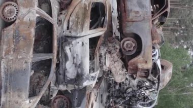 This stock vertical video shows a dump of shot and burned cars in Irpin, Bucha district , grey, flat video