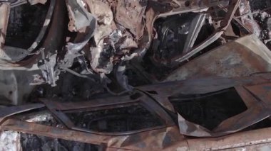 This stock vertical video shows a dump of shot and burned cars in Irpin, Bucha district , grey, flat video