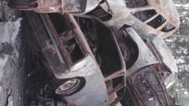 This stock vertical video shows a dump of shot and burned cars in Irpin, Bucha district , grey, flat video