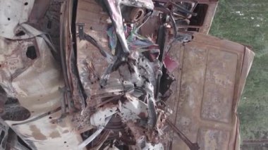 This stock vertical video shows a dump of shot and burned cars in Irpin, Bucha district , grey, flat video